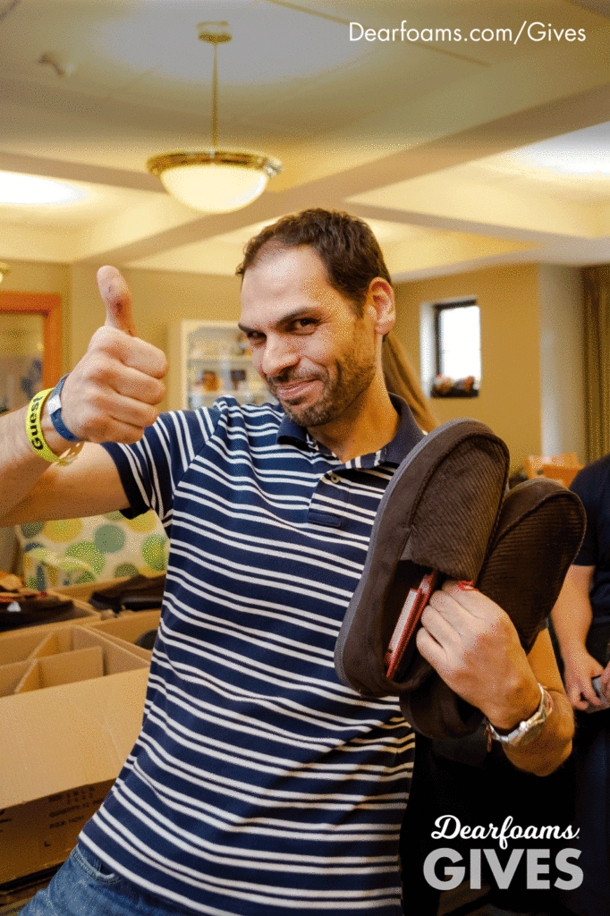 Guest gives thumbs up while holding slippers.