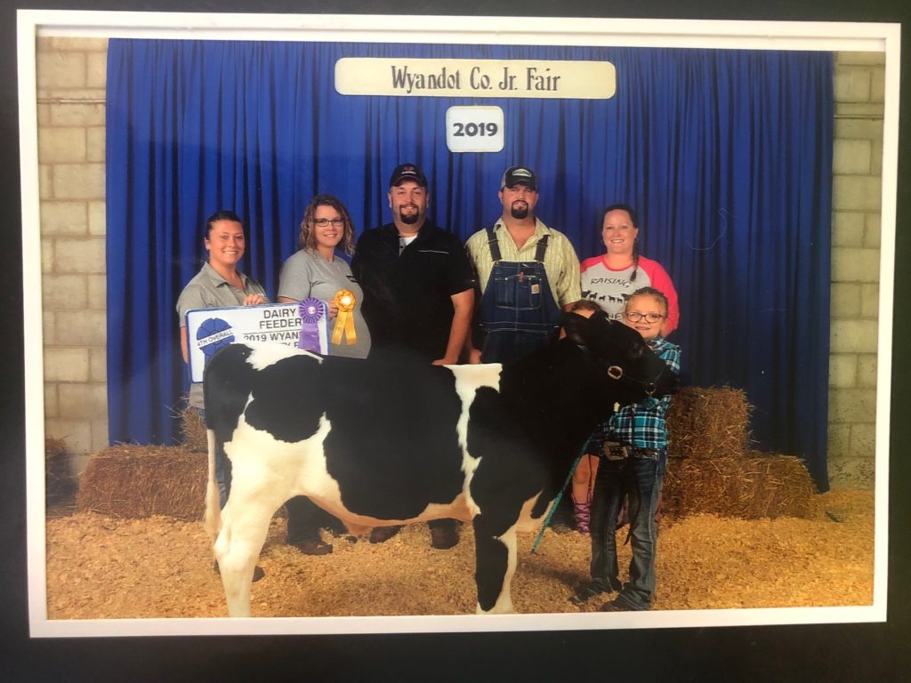 Paige stands with members of her family and the calf she sold.