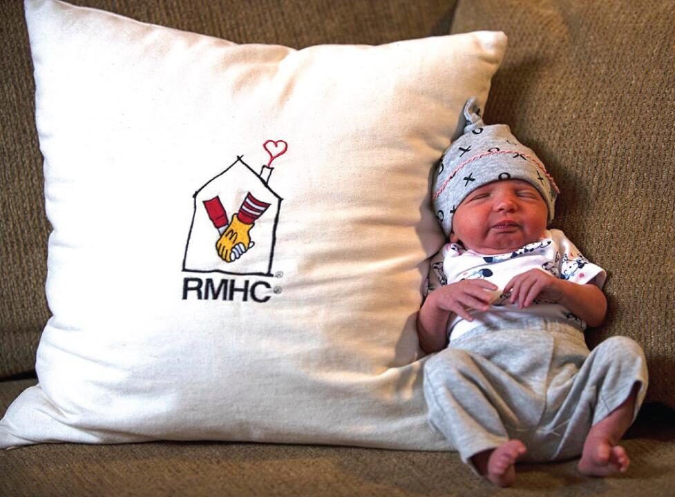 newborn infant baby sleeping next to pillow with RMHC Logo